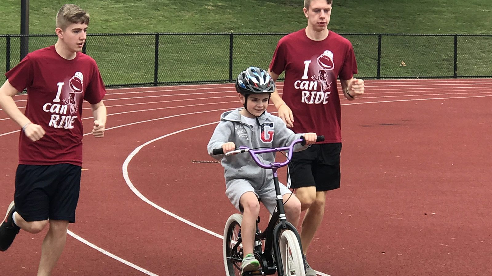 child on bike with two runners