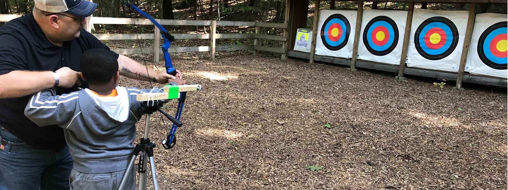 Student with instructor shooting bow and arrow at targets