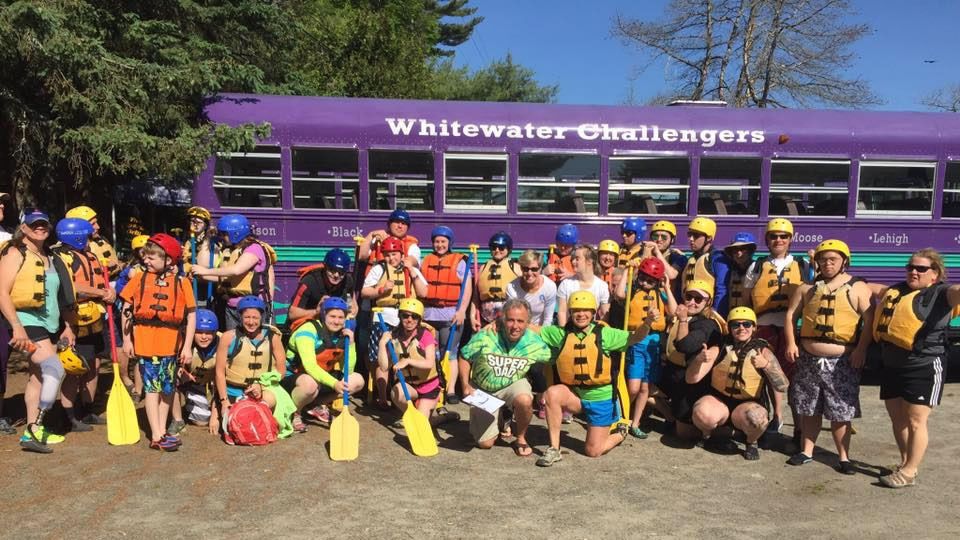 Whitewater rafting group posing in fron of Whitewater Challengers bus