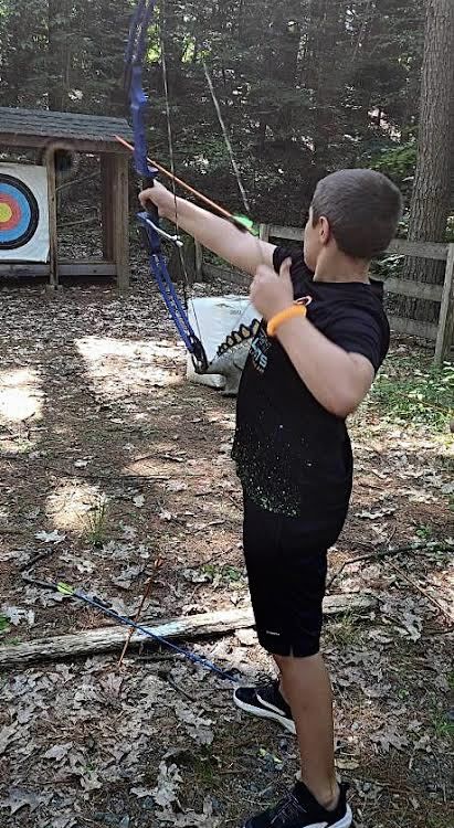 Boy aiming at target with bow & arrow