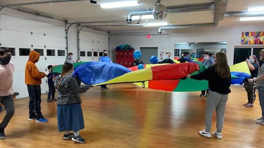 group in circle holding colorful gym parachute