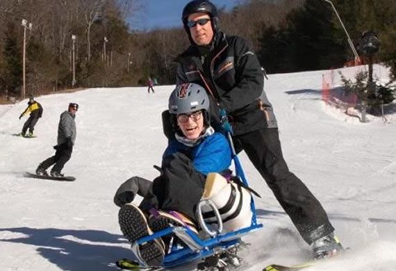 a sled skier with helper
