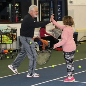 Tennis instructor hi-fiving student