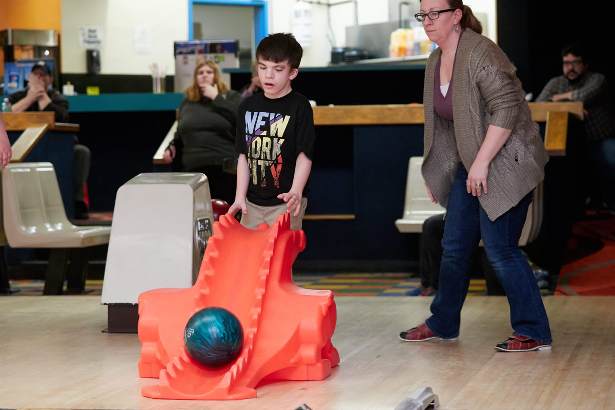 Boy sending bowling ball down ramp