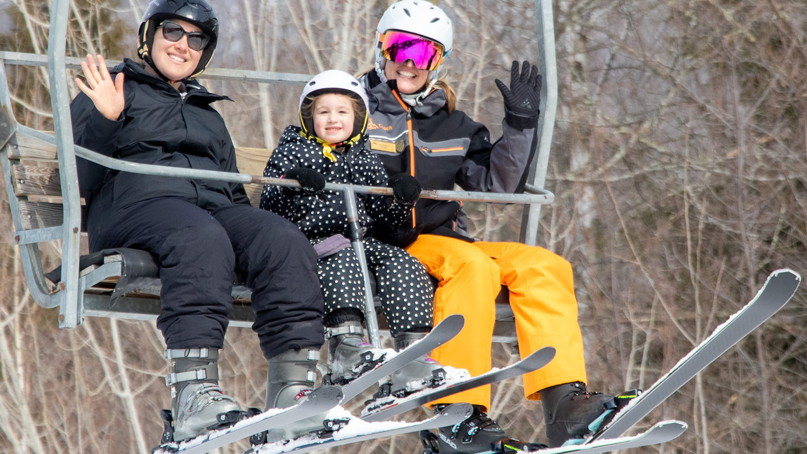 Two adult skiiers and child on charilift
