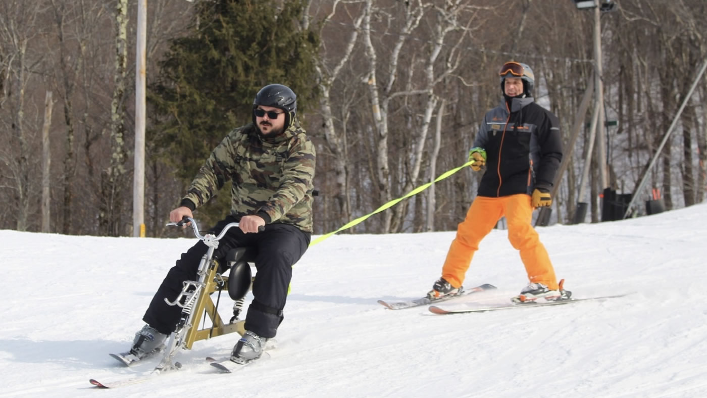 Skiier led by bike rider