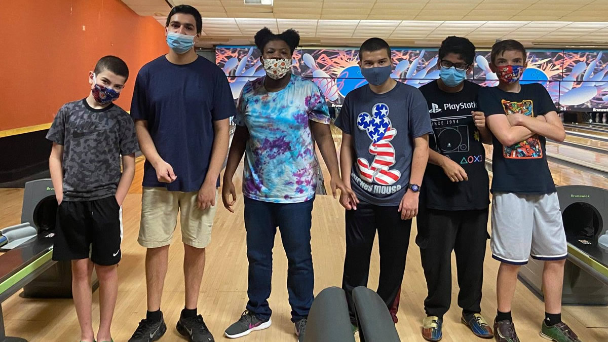Teens posing in front of bowling lane