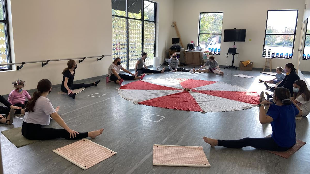 group on mats around a gym parachute
