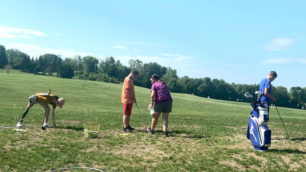 4 young adults at a golf driving range